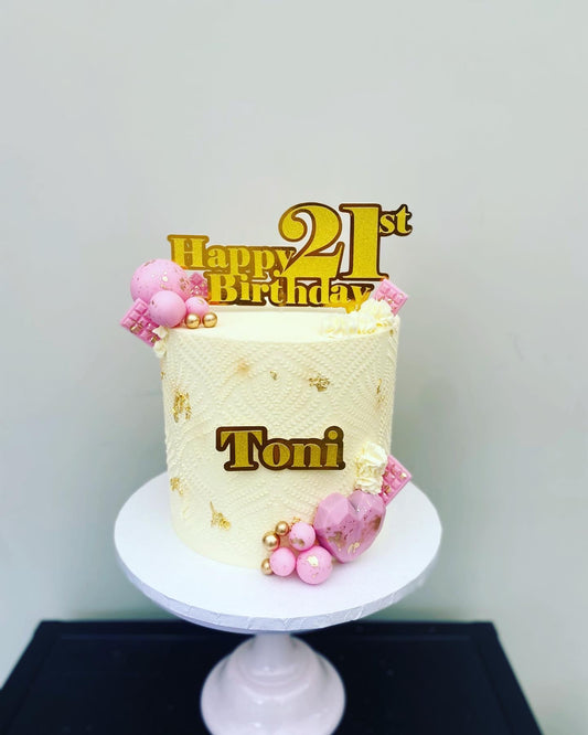 Cream buttercream cake with gold and pink decorations